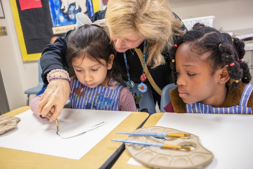 Teacher helps students with their art technique