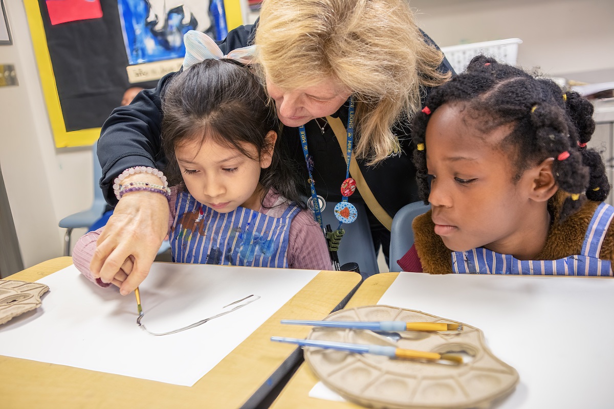 Teacher helps students with theri art technique